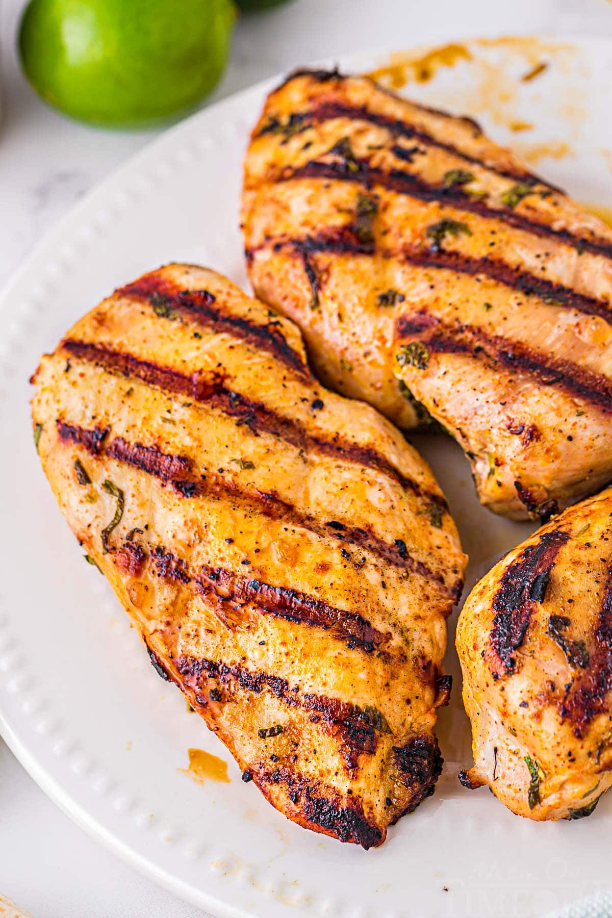 three grilled chicken breasts on white plate that were marinated in a cilantro lime marinade.