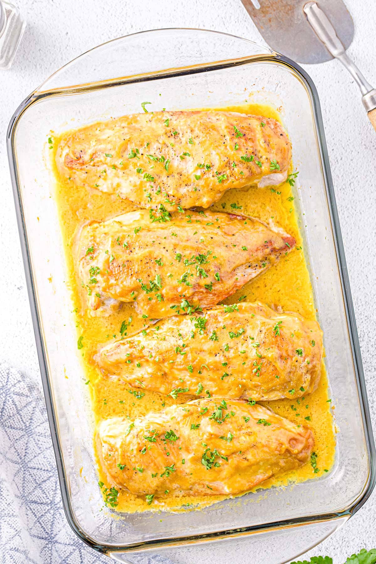 top down look at baked honey mustard chicken in glass baking dish with a lot of honey mustard sauce in the dish.