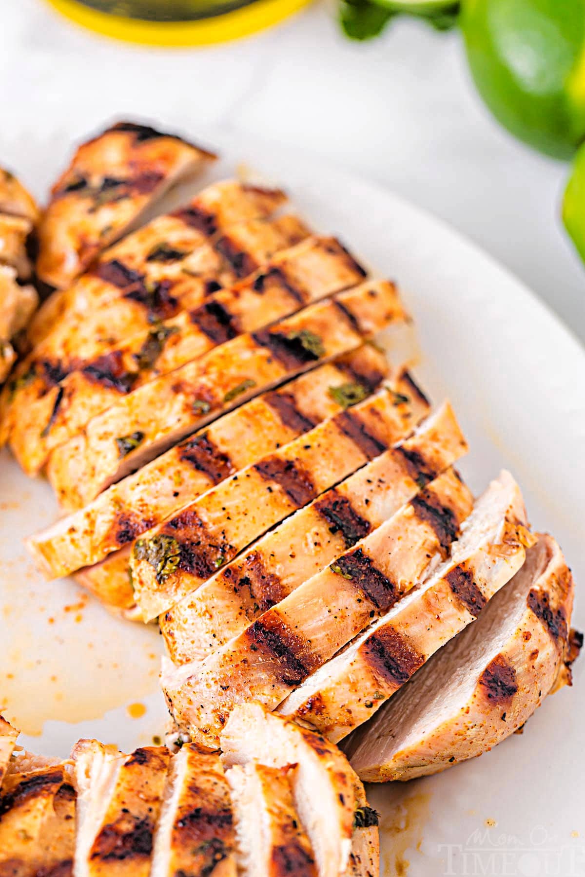 up close look at grilled chicken breast sliced into strips on a white plate.