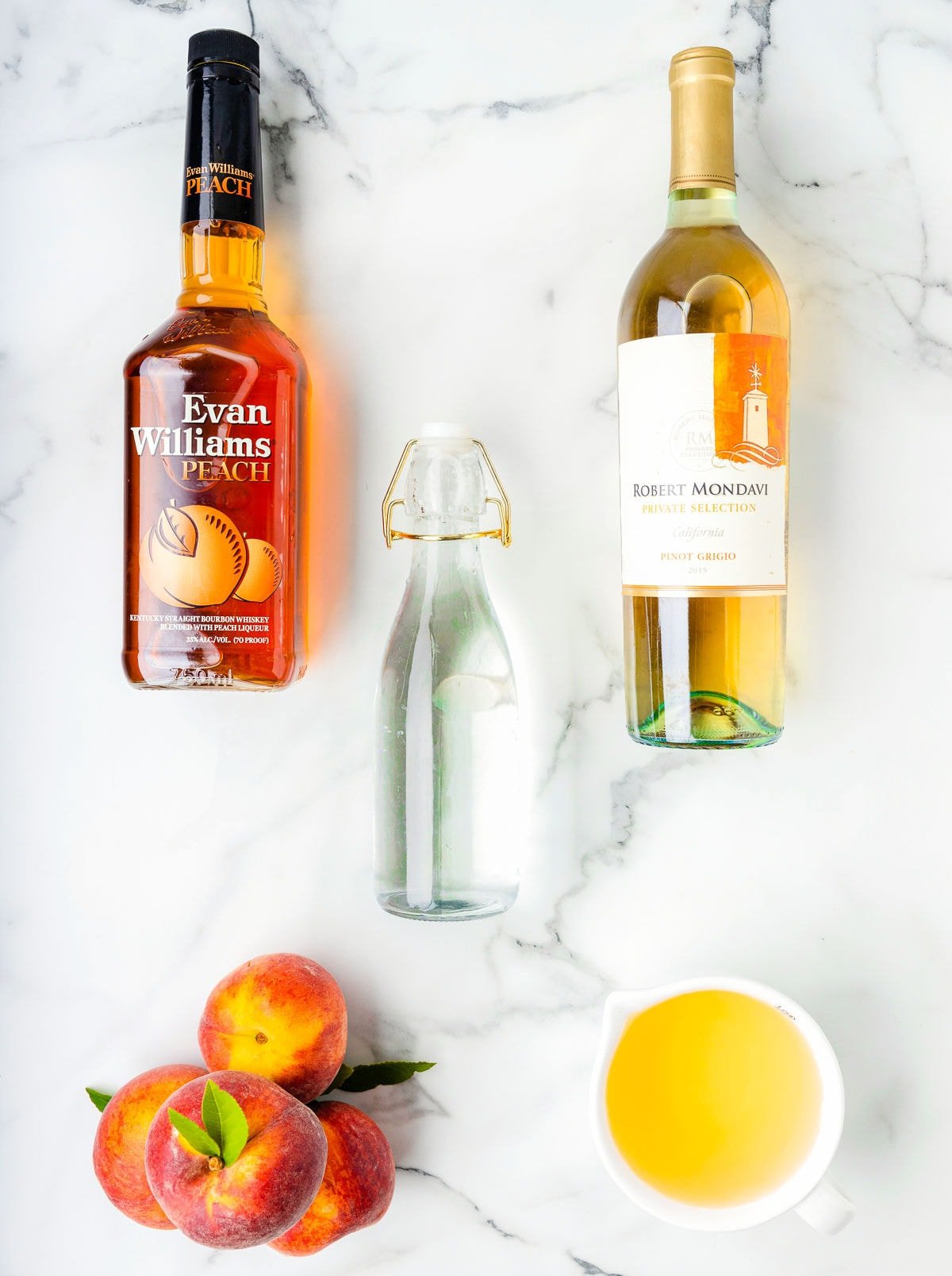 top down look at peach sangria ingredients placed on a white marble surface.