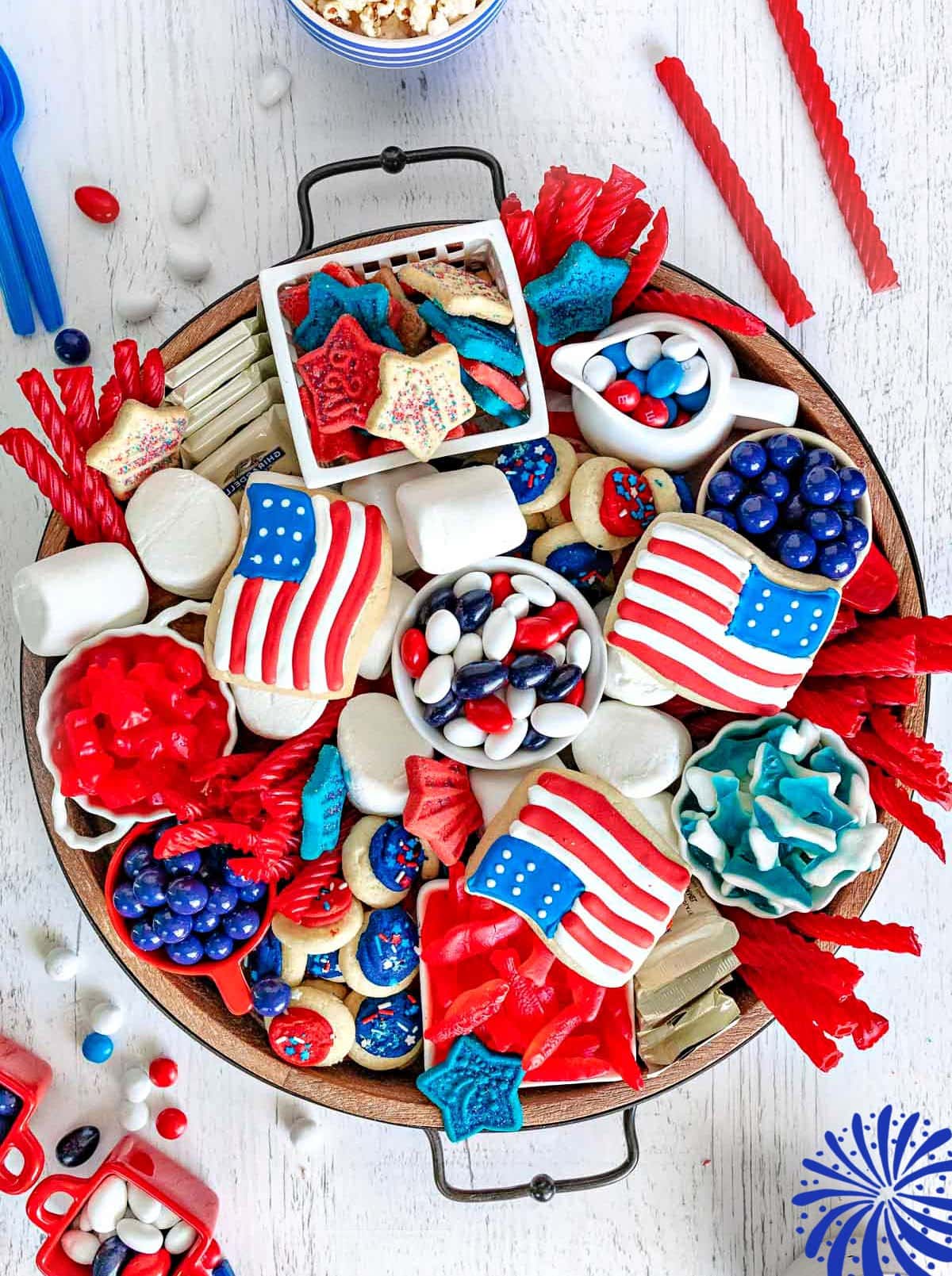 top down look at wood charcuterie board loaded with red white and blue desserts for 4th of july. cookies, candy and all sorts of colorful treats.