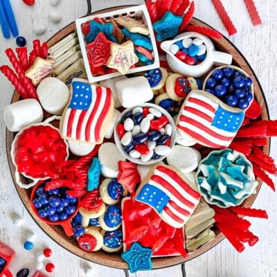 top down look at wood charcuterie board loaded with red white and blue desserts for 4th of july. cookies, candy and all sorts of colorful treats.