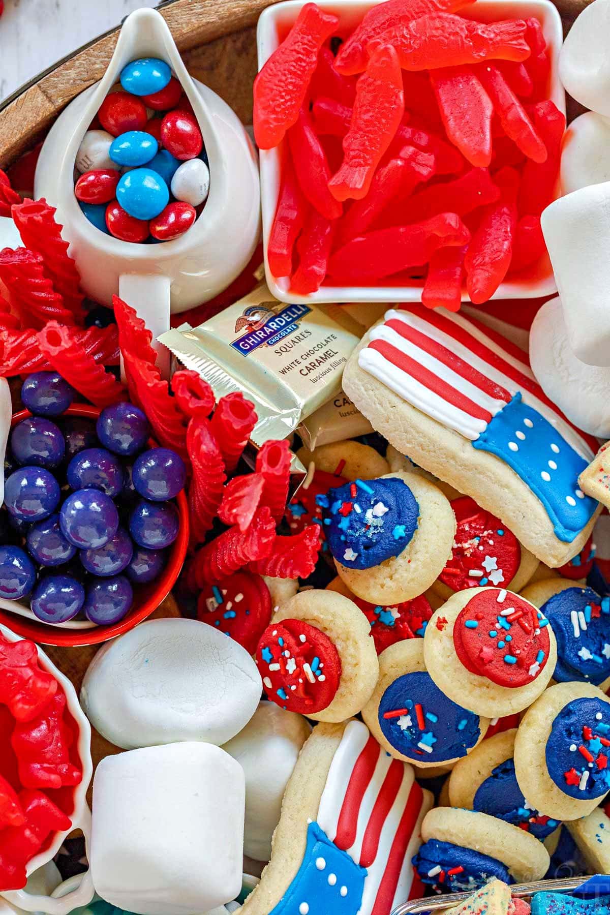 close up top down view of 4th of july cookies and treats on a large round board.