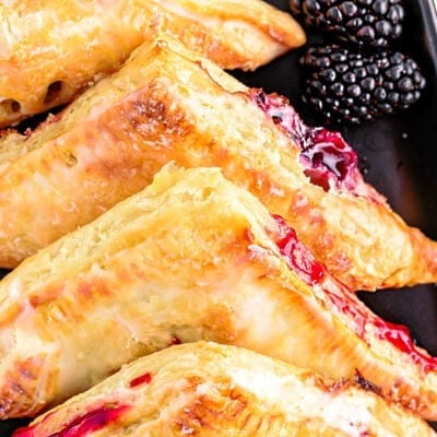 close up look at turnovers with blackberry filling lined up on a black plate.