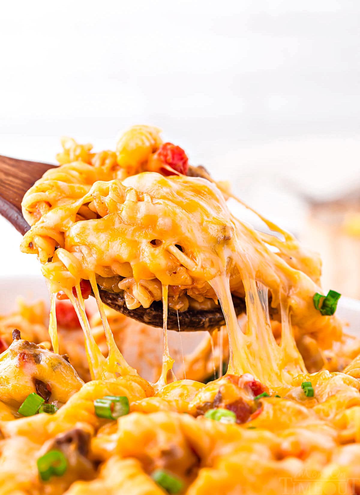 spoonful of cheeseburger casserole being pulled out of the baking dish with a seriously yummy cheese pull shot.