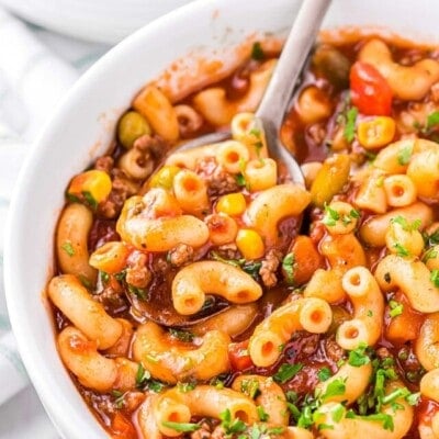 bowl full of macaroni soup with a spoon dipped in and ready to scoop out a bite of the soup.