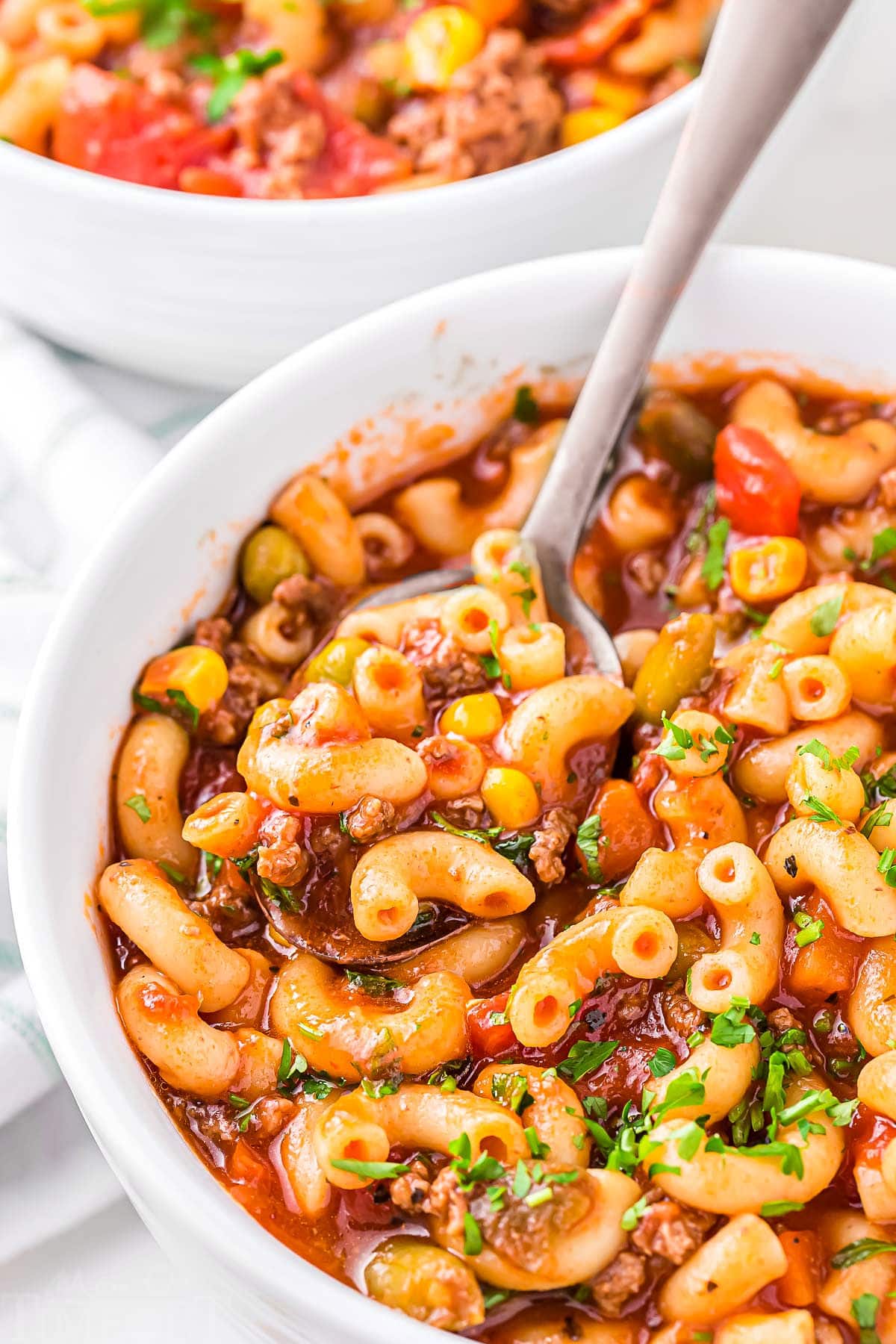 bowl full of macaroni soup with a spoon dipped in and ready to scoop out a bite of the soup.