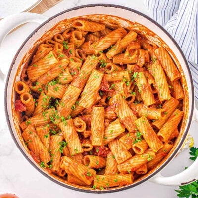 top down look at one pot pasta in a white dutch oven garnished with fresh parsley.