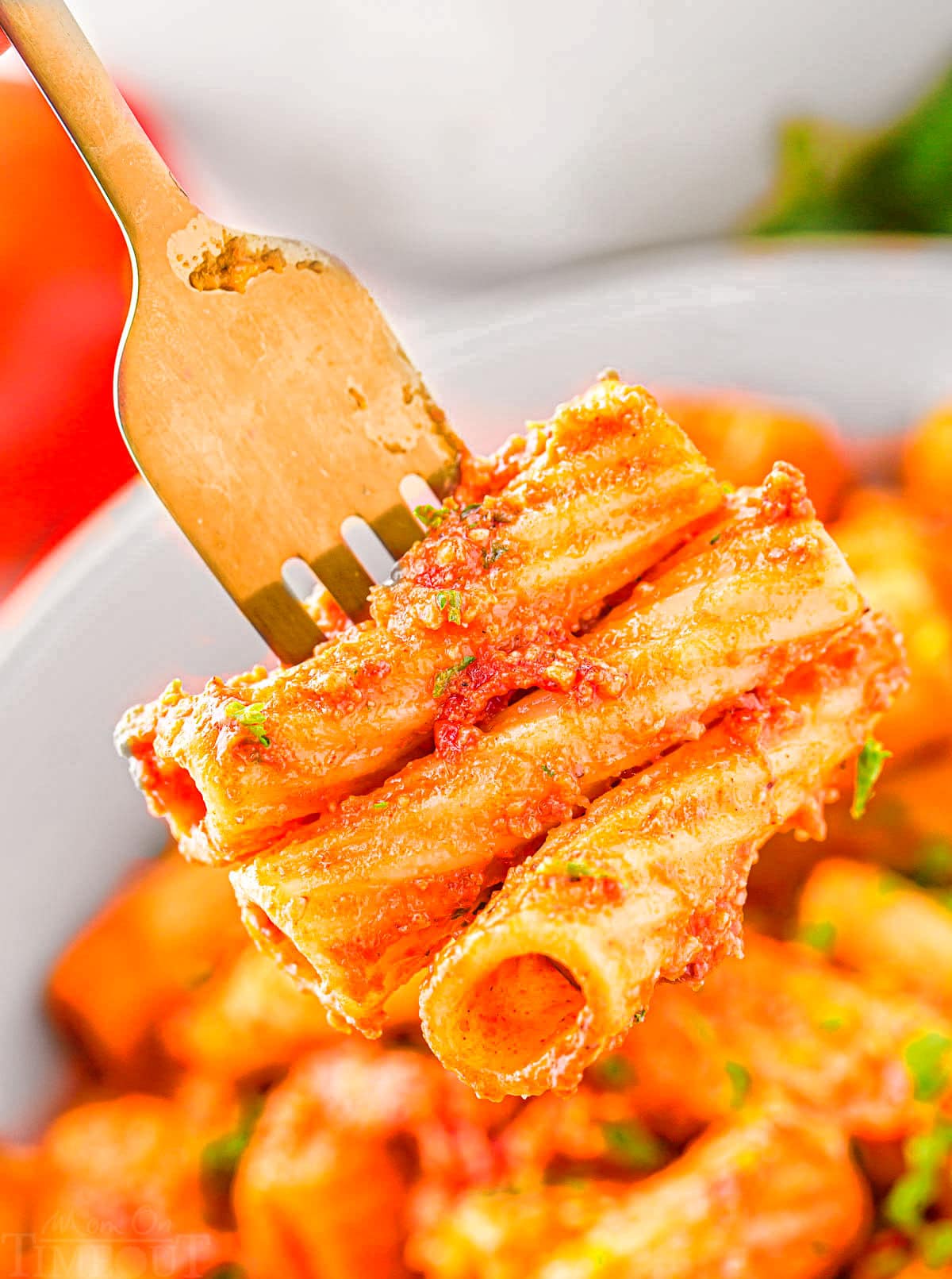 fork with three pieces of pasta on it held above a bowl.