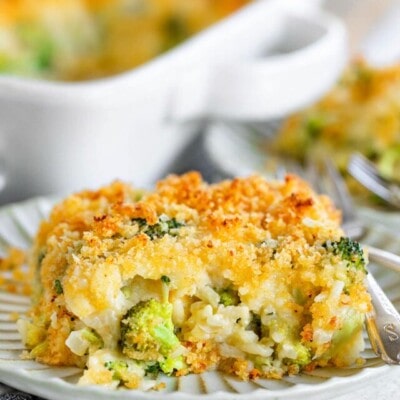 serving of broccoli rice casserole on a small decorative white plate with the casserole dish in the background.