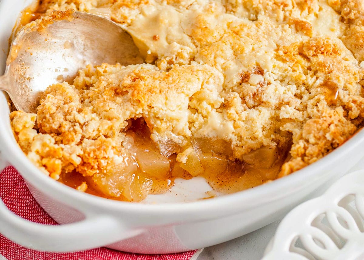 top down look at easy apple cobbler recipe in a white baking dish with several servings removed and an antique serving spoon in the dish.