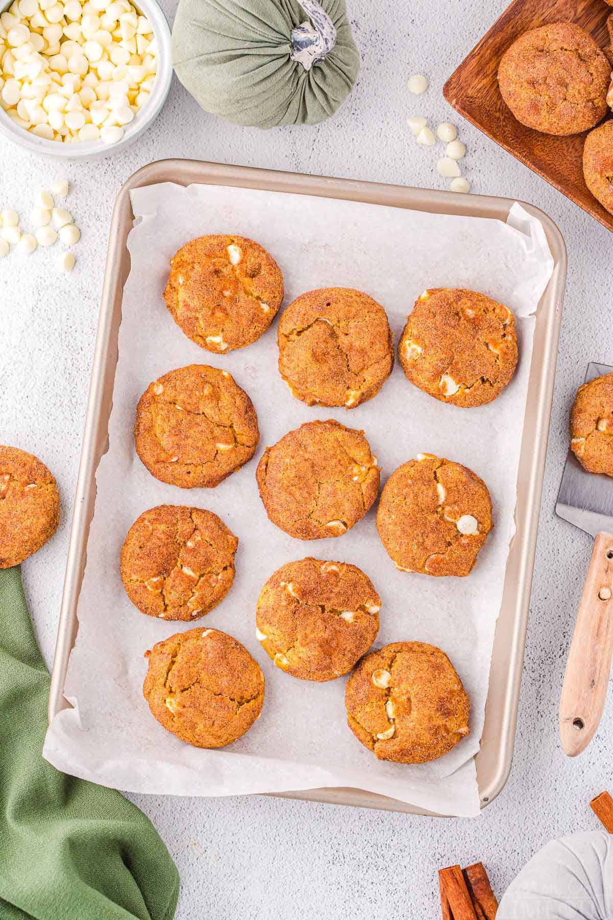 top down look at cookies baked on a baking sheet and ready to enjoy. green napkin in the bottom corner and more cookies scattered about.