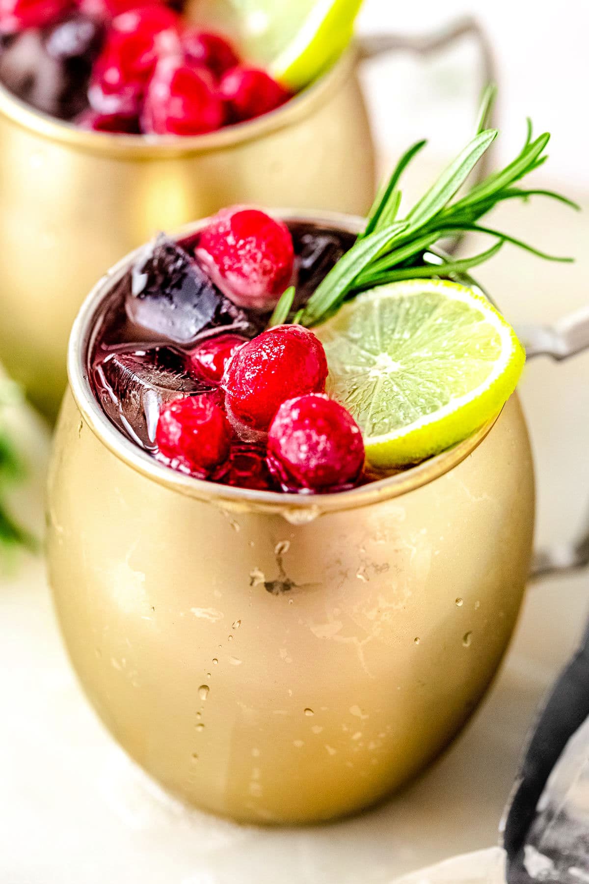 close up look at garnishes on top of cranberry moscow mule. another mule is behind the front one.