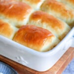 golden brown parker house rolls slathered with butter and still in the white baking dish.