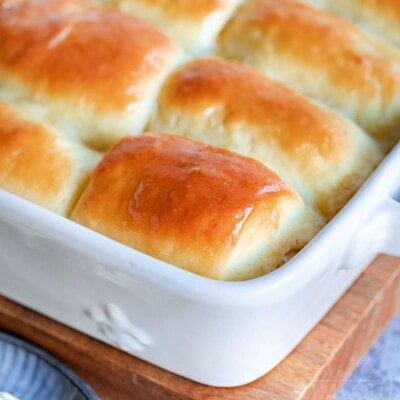 golden brown parker house rolls slathered with butter and still in the white baking dish.