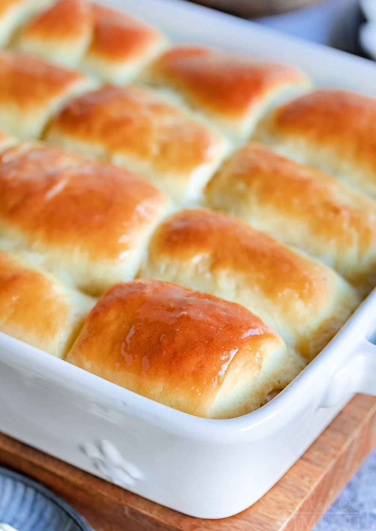 golden brown parker house rolls slathered with butter and still in the white baking dish.