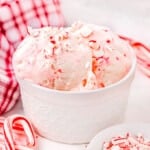 white bowl of peppermint ice cream with mini candy canes scattered about.