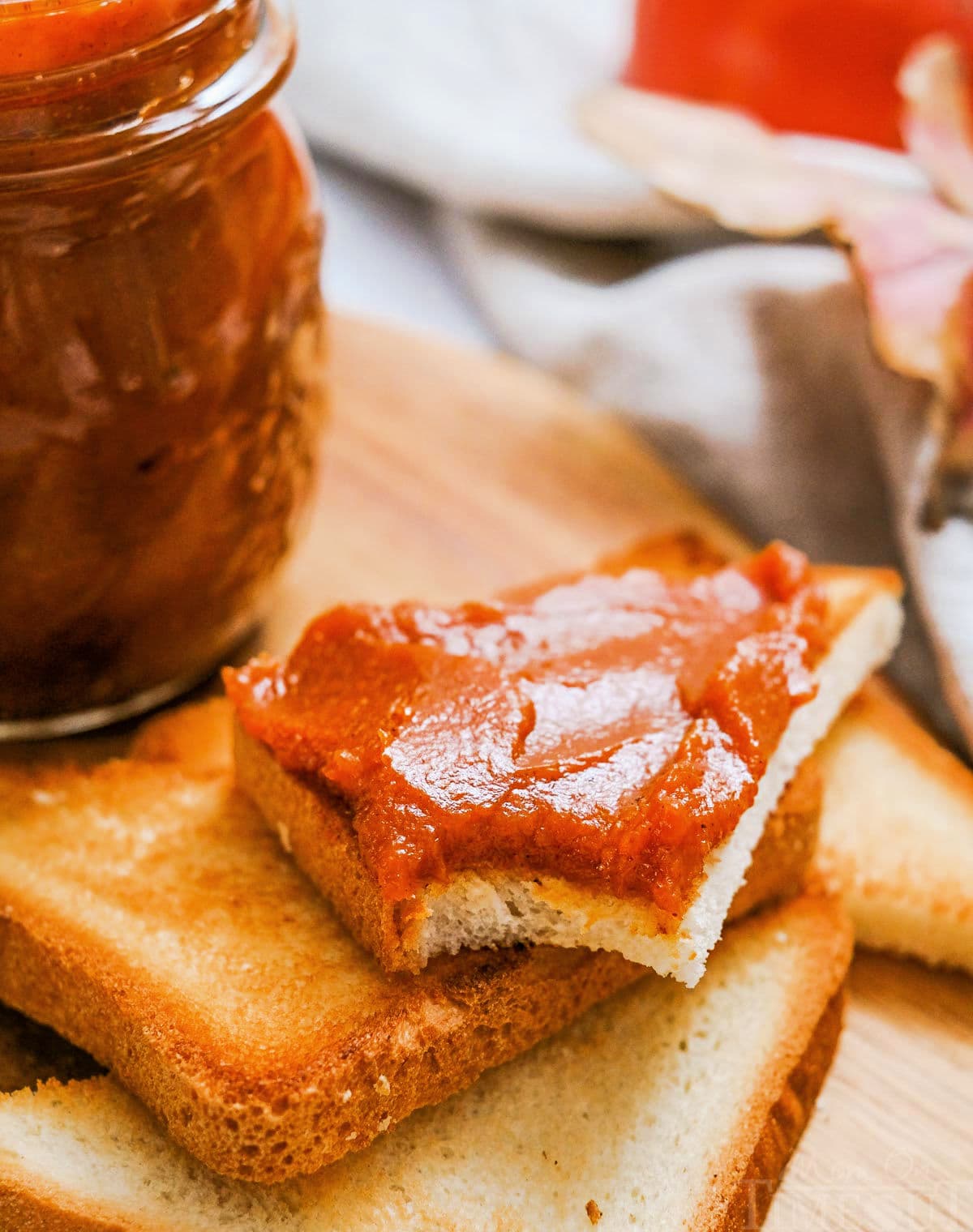 stack of toast with top piece cut into triangle and smeared with pumpkin butter. jar of pumpkin butter can be seen to the side.