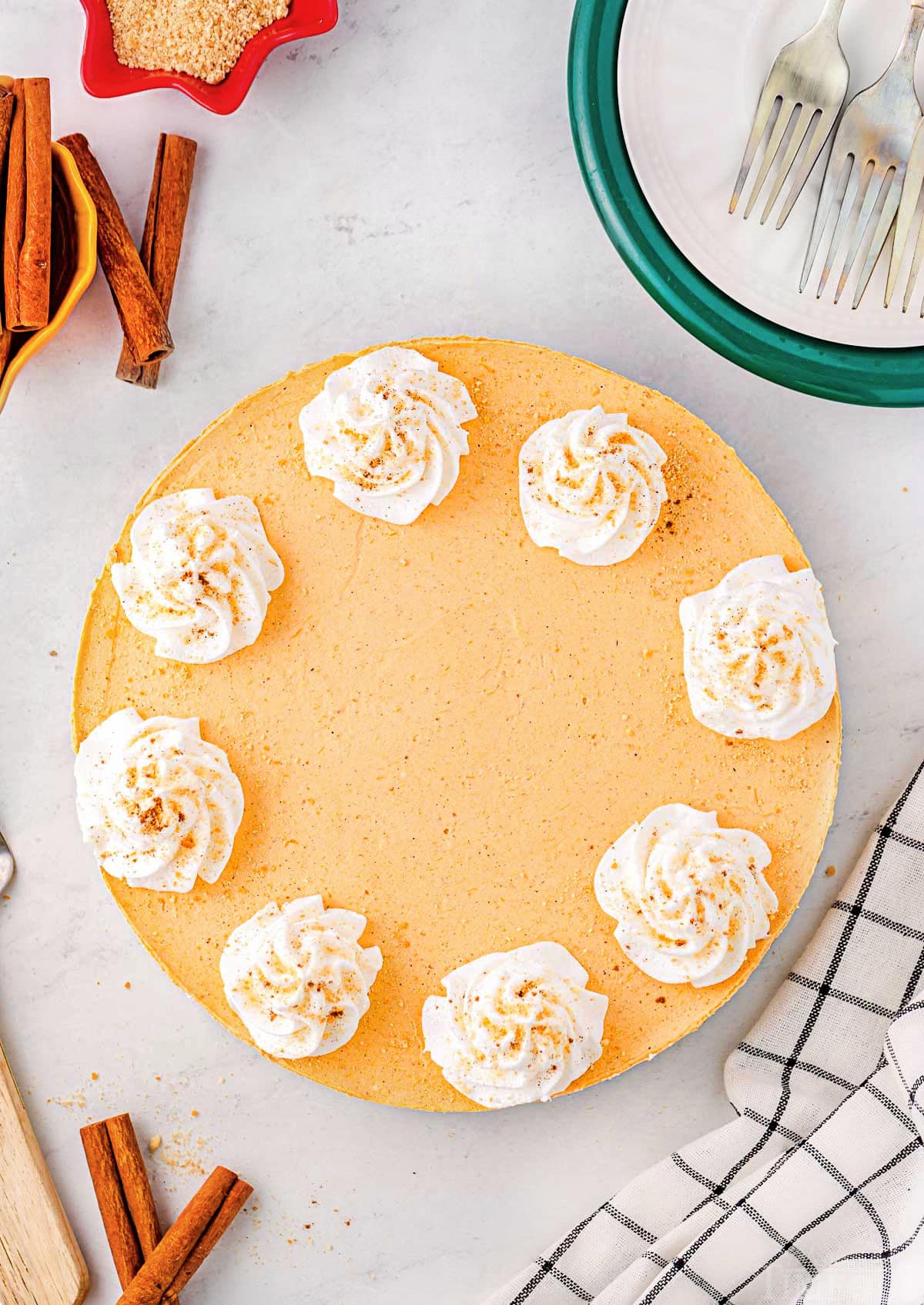 top down look at pumpkin cheesecake with whipped cream dollops ready to be served. 