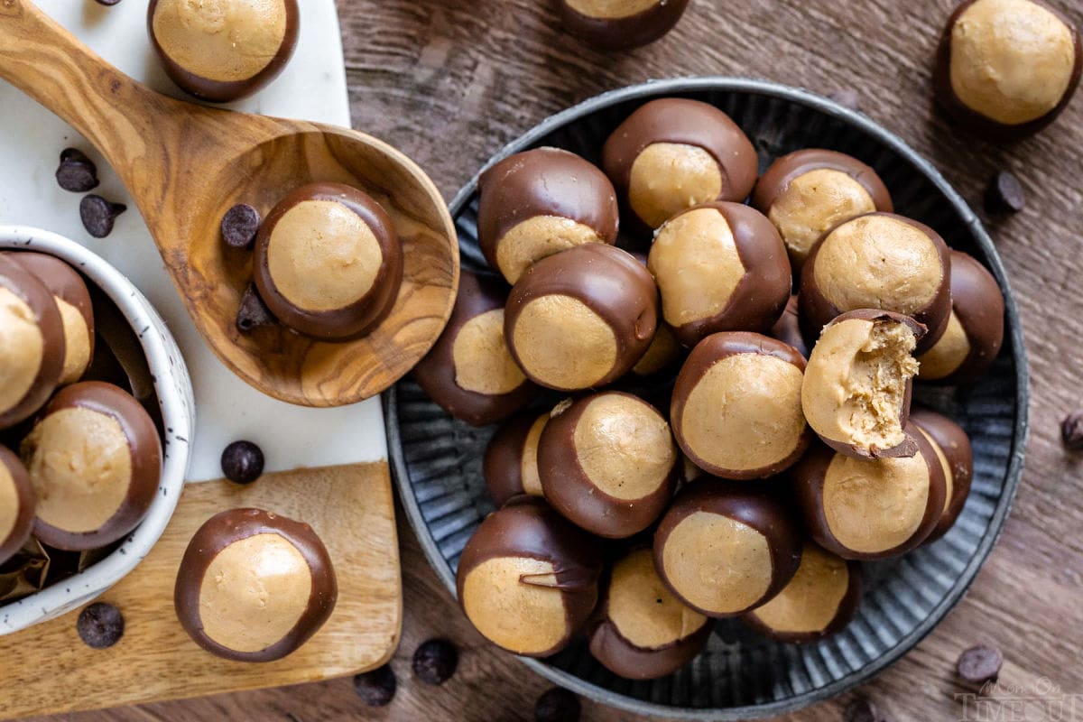 top down look at buckeyes on a silver plate and also in a white mug. more candies are scattered about.