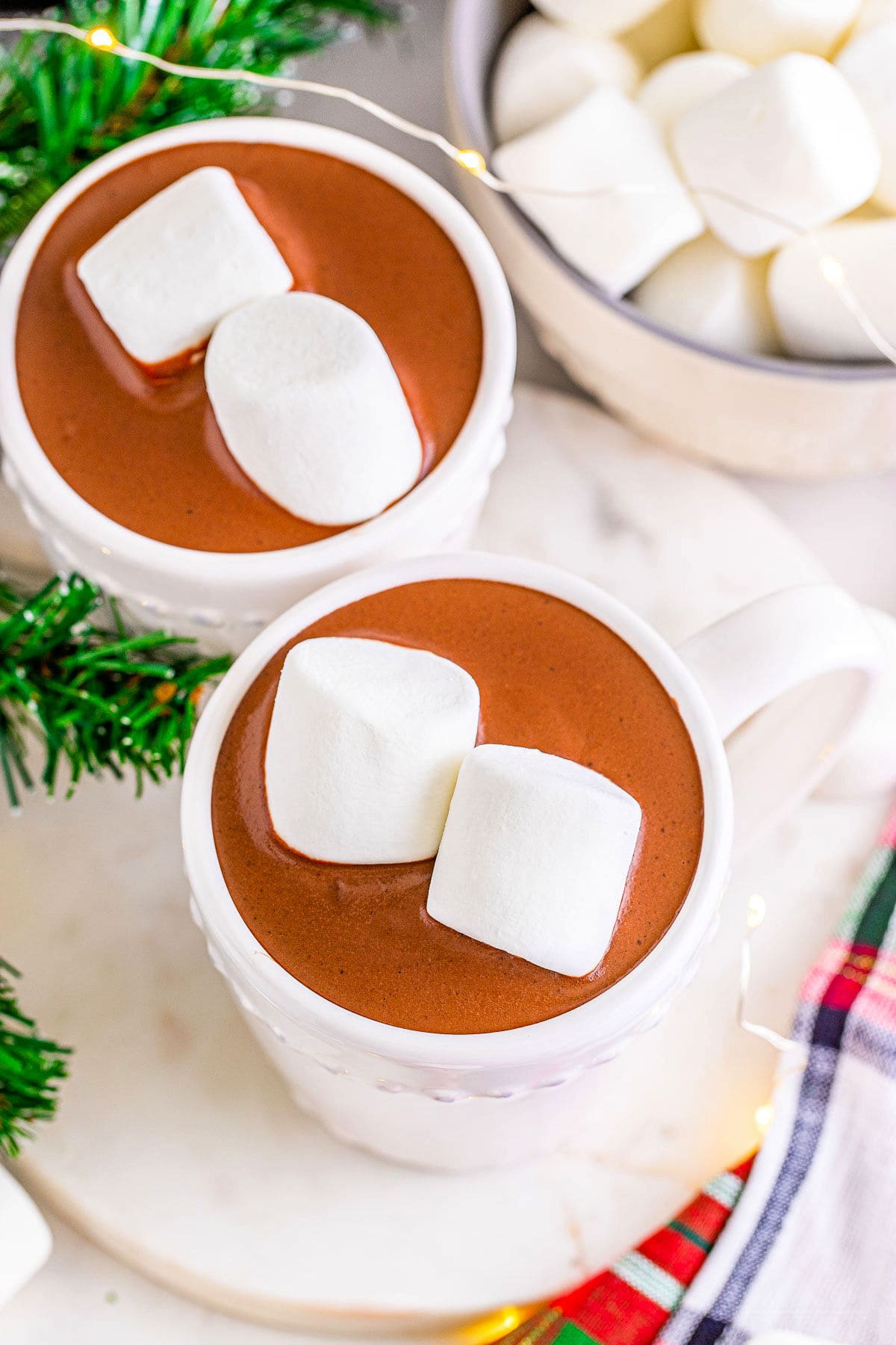 top down shot of two mugs of hot chocolate and bowl of jumbo marshmallows.