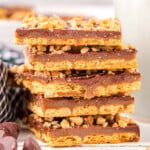 six pieces of graham cracker toffee stacked on top of each other with some chocolate chips scattered in front.