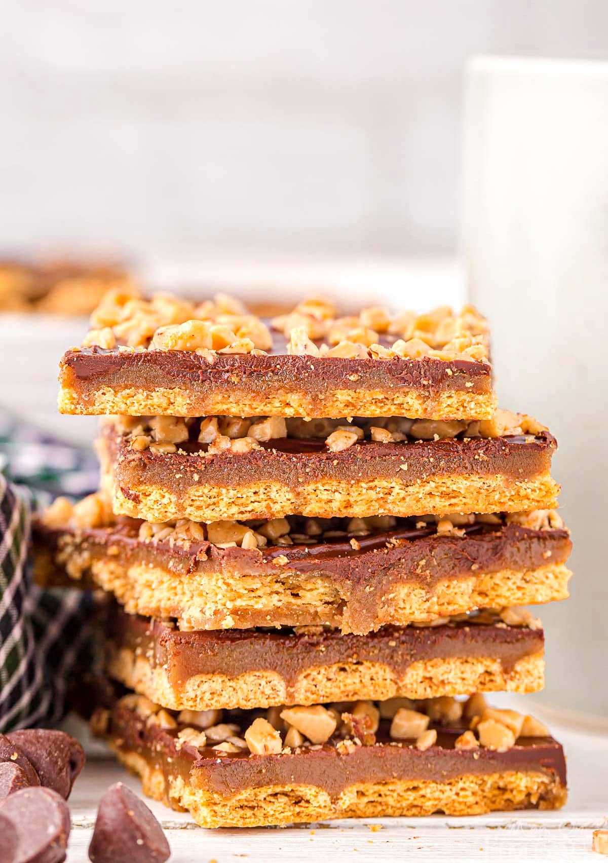 six pieces of graham cracker toffee stacked on top of each other with some chocolate chips scattered in front.