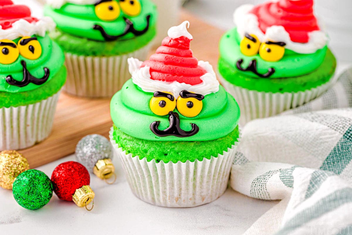 wide shot of four grinch cupcakes in white cupcake liners all decorated and ready to be enjoyed.