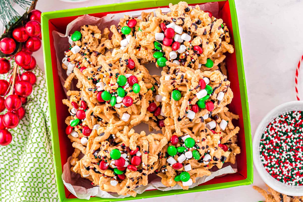 haystack candy stacked on top of each in a christmas box. the haystacks are topped with chocolate, marshmallows and m and m candies.