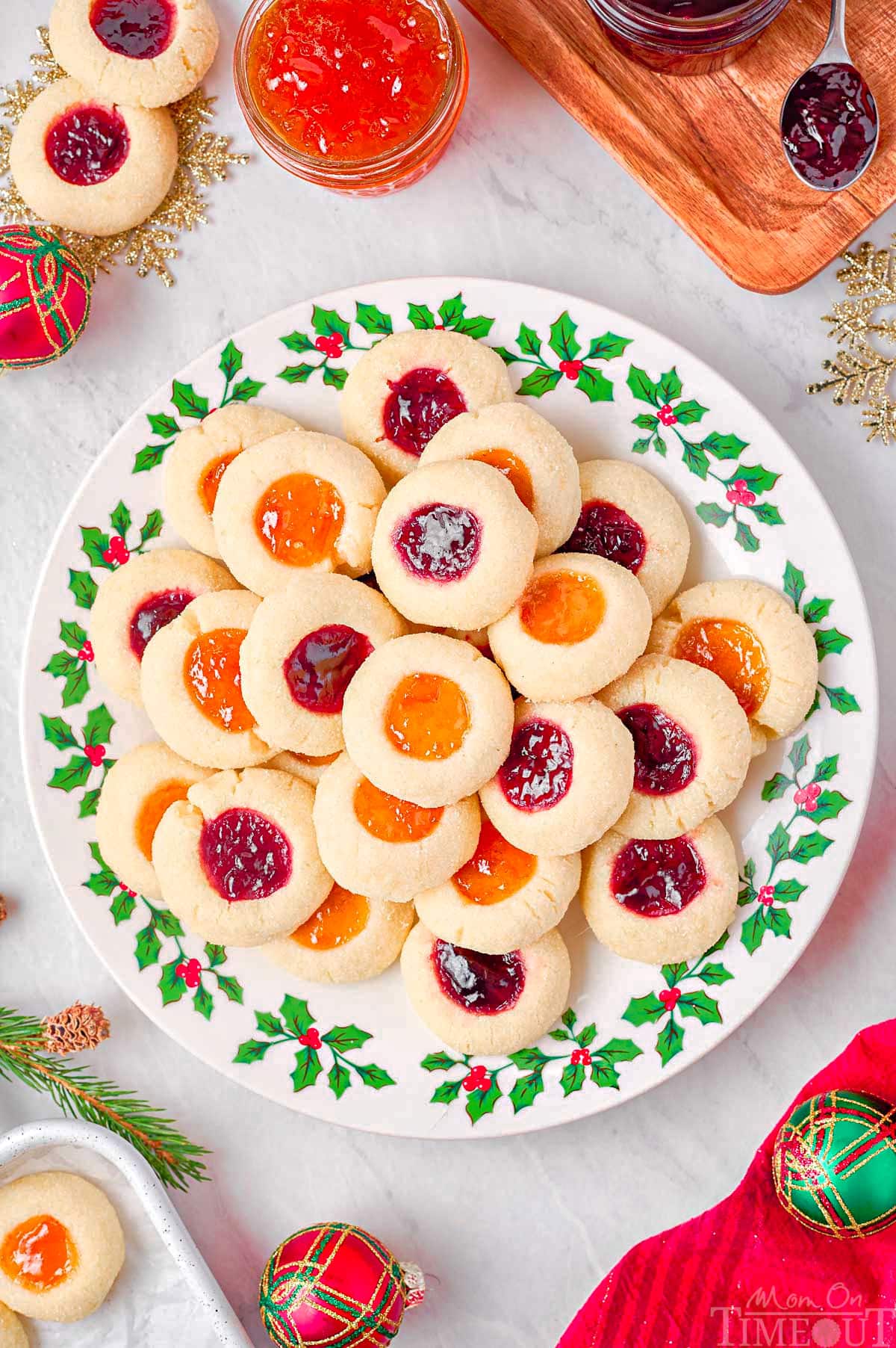 top down look at christmas plate piled high with thumbprint cookies filled with raspberry and apricot jam