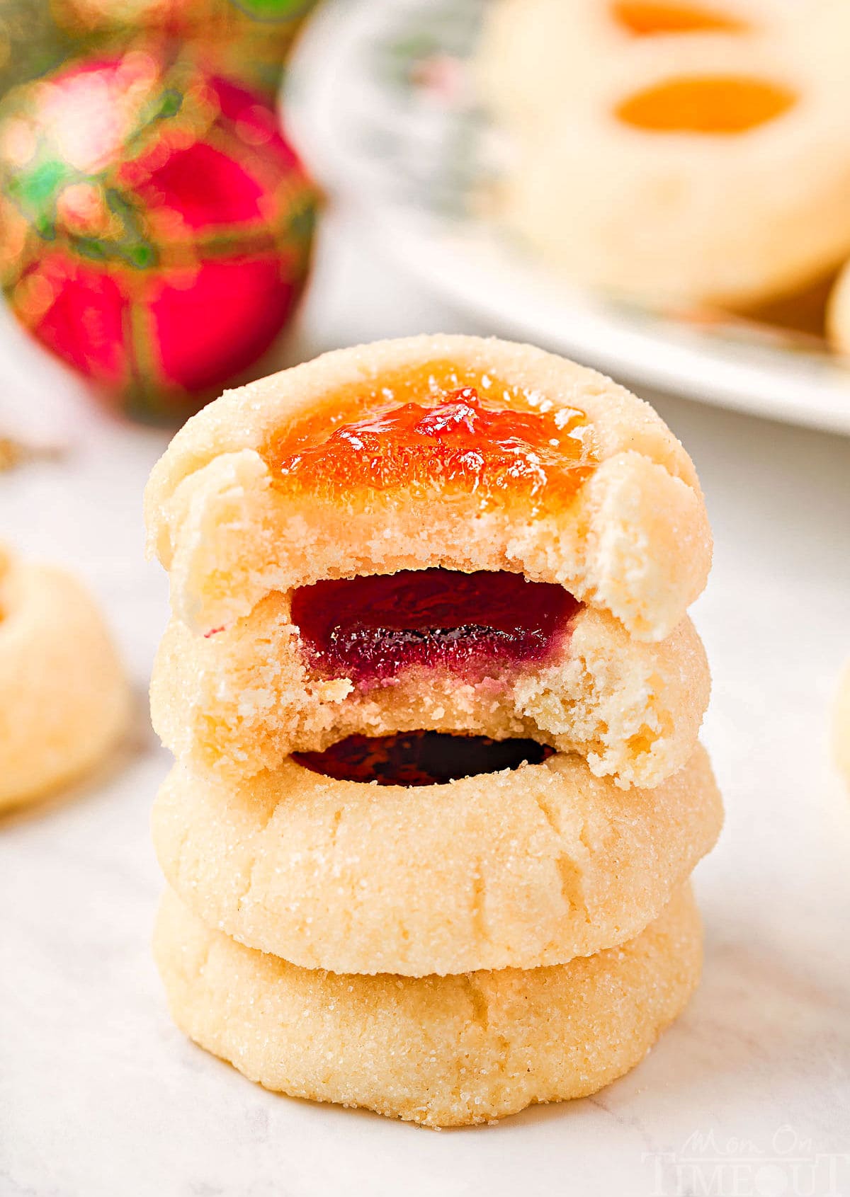 four cookies stacked with jam centers. top two cookies have bites taken out of them.