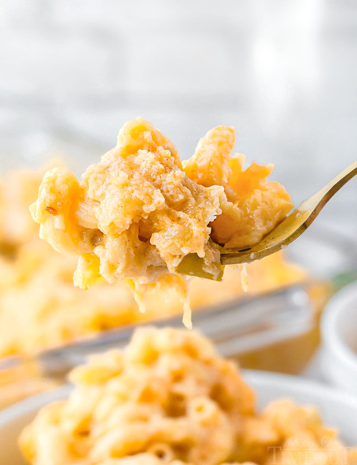 forkful of mac and cheese held above the bowl filled with the mac and cheese.