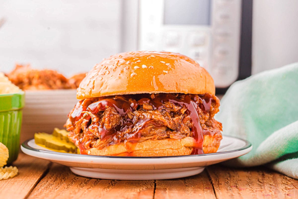 pulled pork sandwich sitting on plate in front of an instant pot.