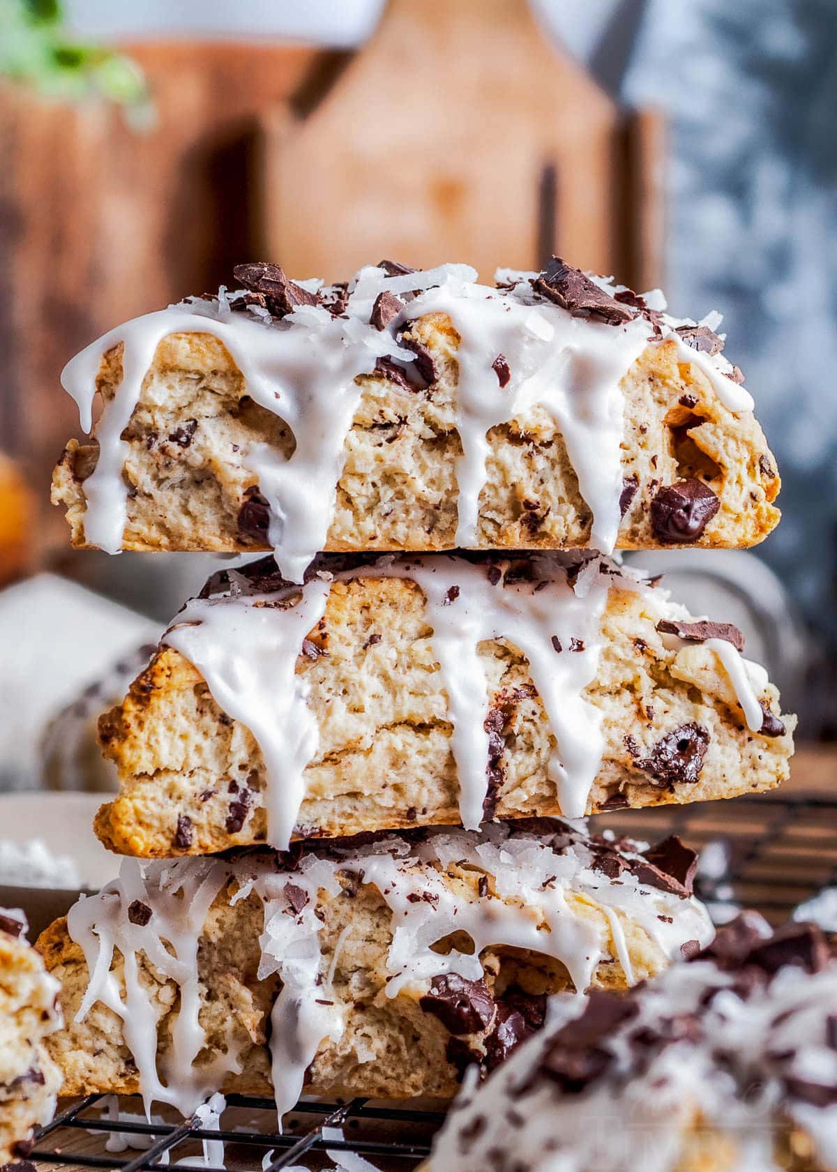 three almond joy scones stacked on a wood board.