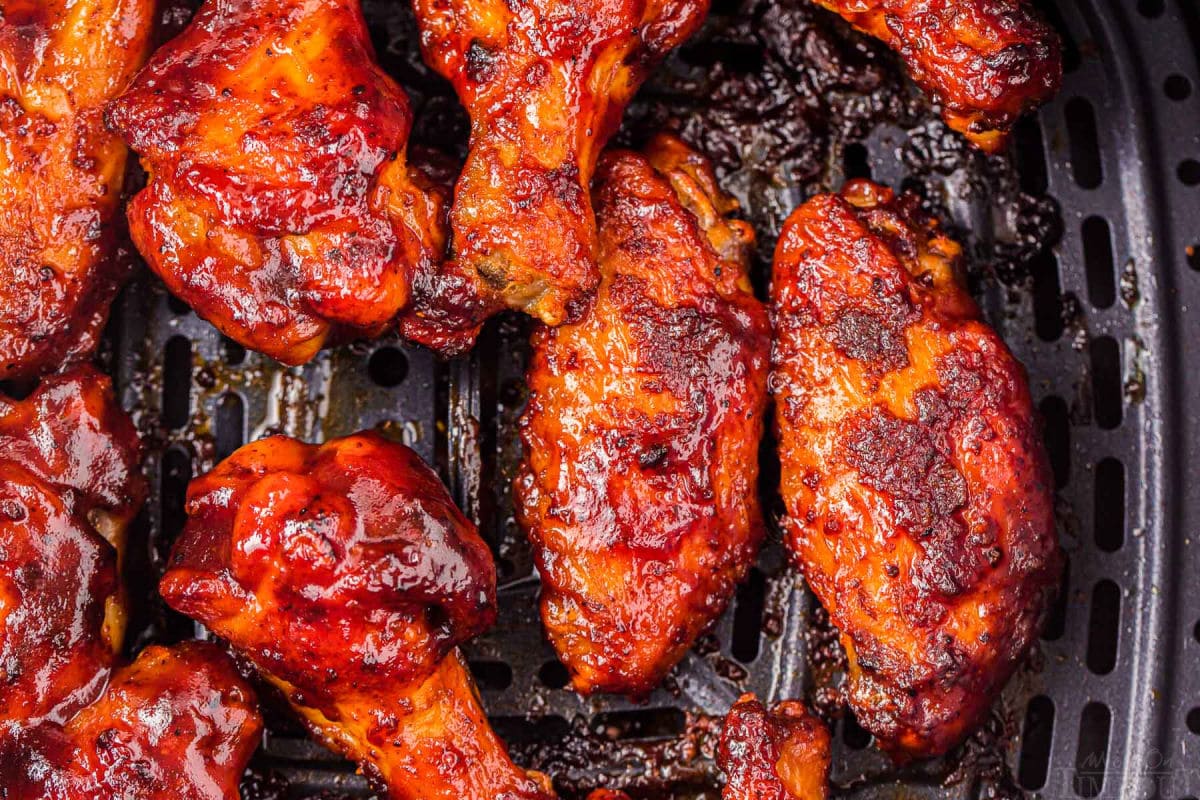 top down look at chicken wings in air fryer brushed with barbecue sauce.