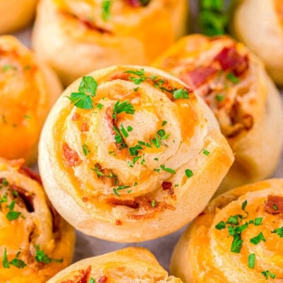 pinwheels recipe made with bacon and cheddar stacked on a plate and topped with freshly chopped parsley.