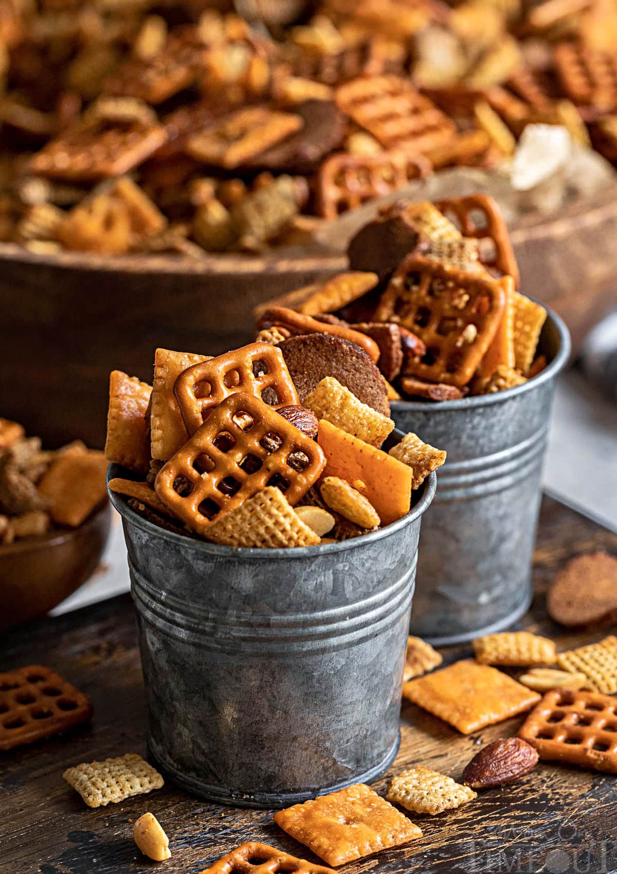 chex mix recipe served in to small metal container with large wood bowl filled with remaining chex mix recipe in the background.