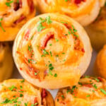 pinwheels recipe made with bacon and cheddar stacked on a plate and topped with freshly chopped parsley.