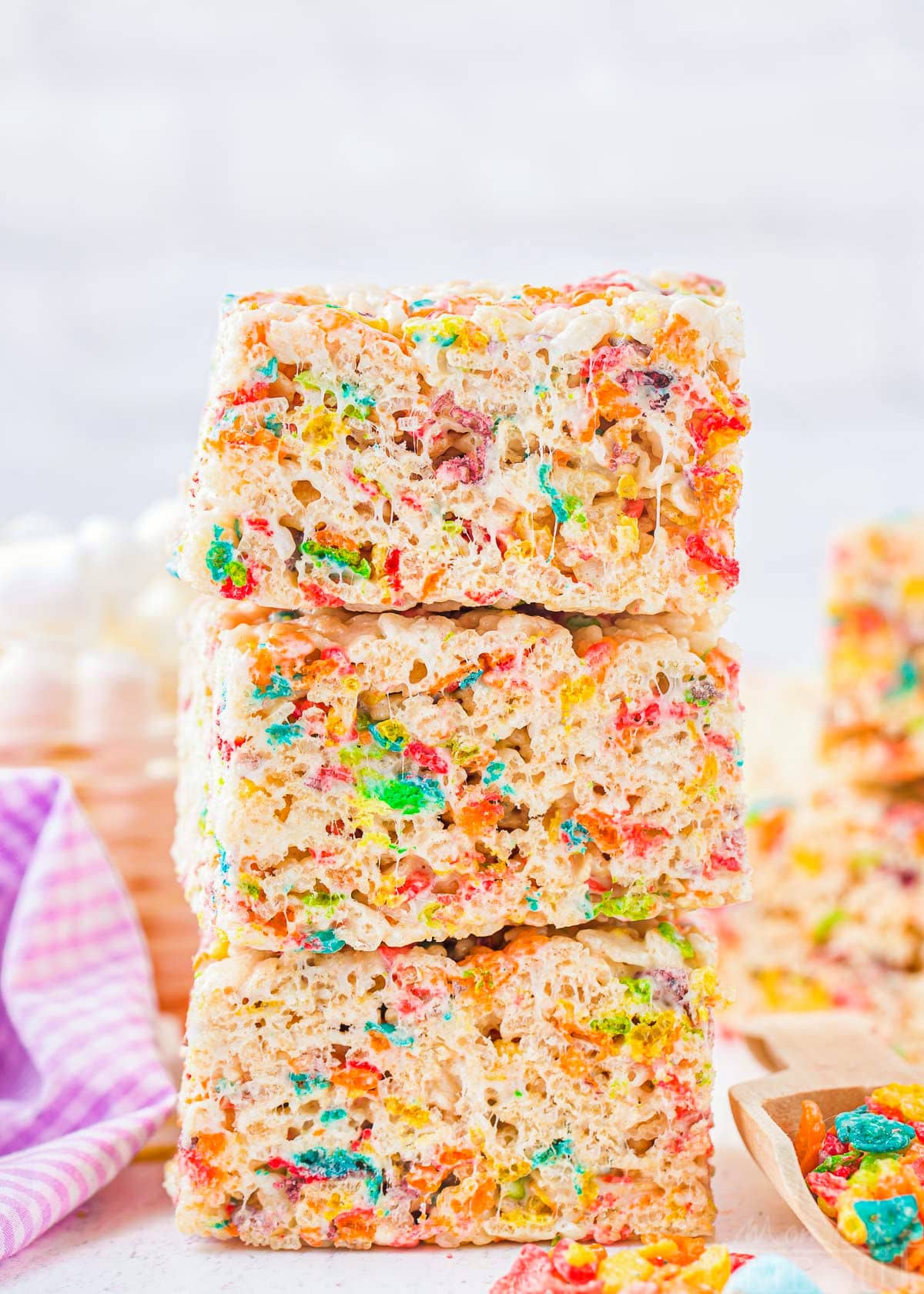 three rainbow rice krispie treats made with fruity pebbles stacked on top of each other.