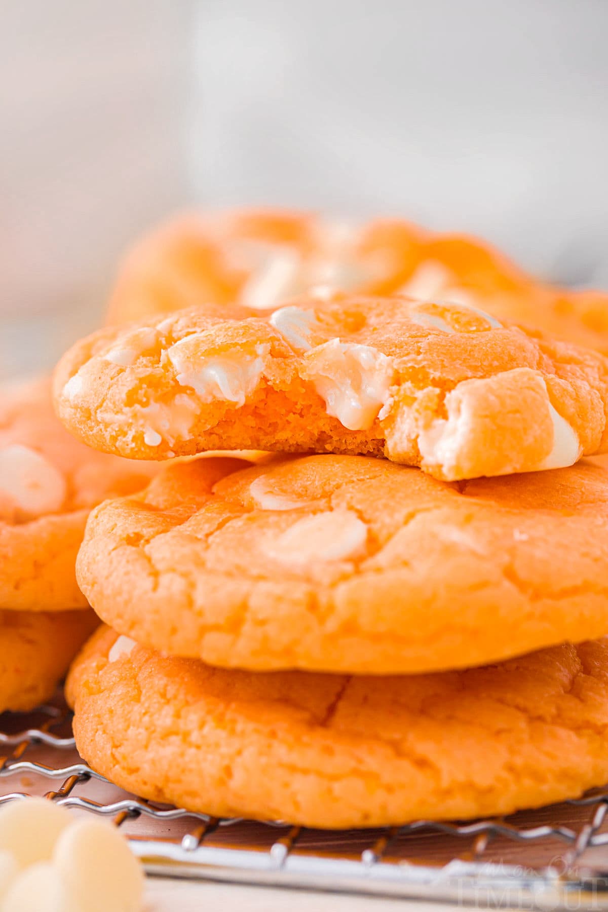 Three creamsicle cookies stacked with the top cookie has a bite taken out of it.