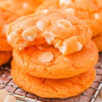 Three creamsicle cookies stacked with the top cookie has a bite taken out of it.