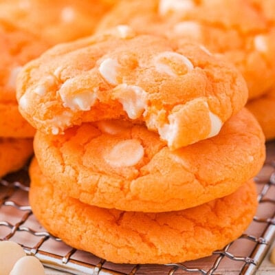 Three creamsicle cookies stacked with the top cookie has a bite taken out of it.