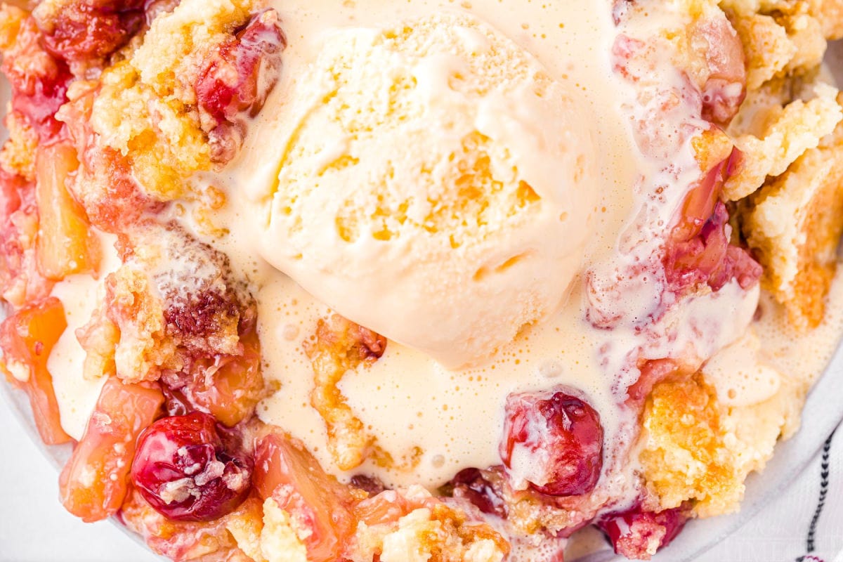 top down close up look at a serving of cherry pineapple dump cake topped with a generous scoop of vanilla ice cream.