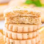 lemon shortbread cookies stacked about 10 high with the top cookie broken in half.