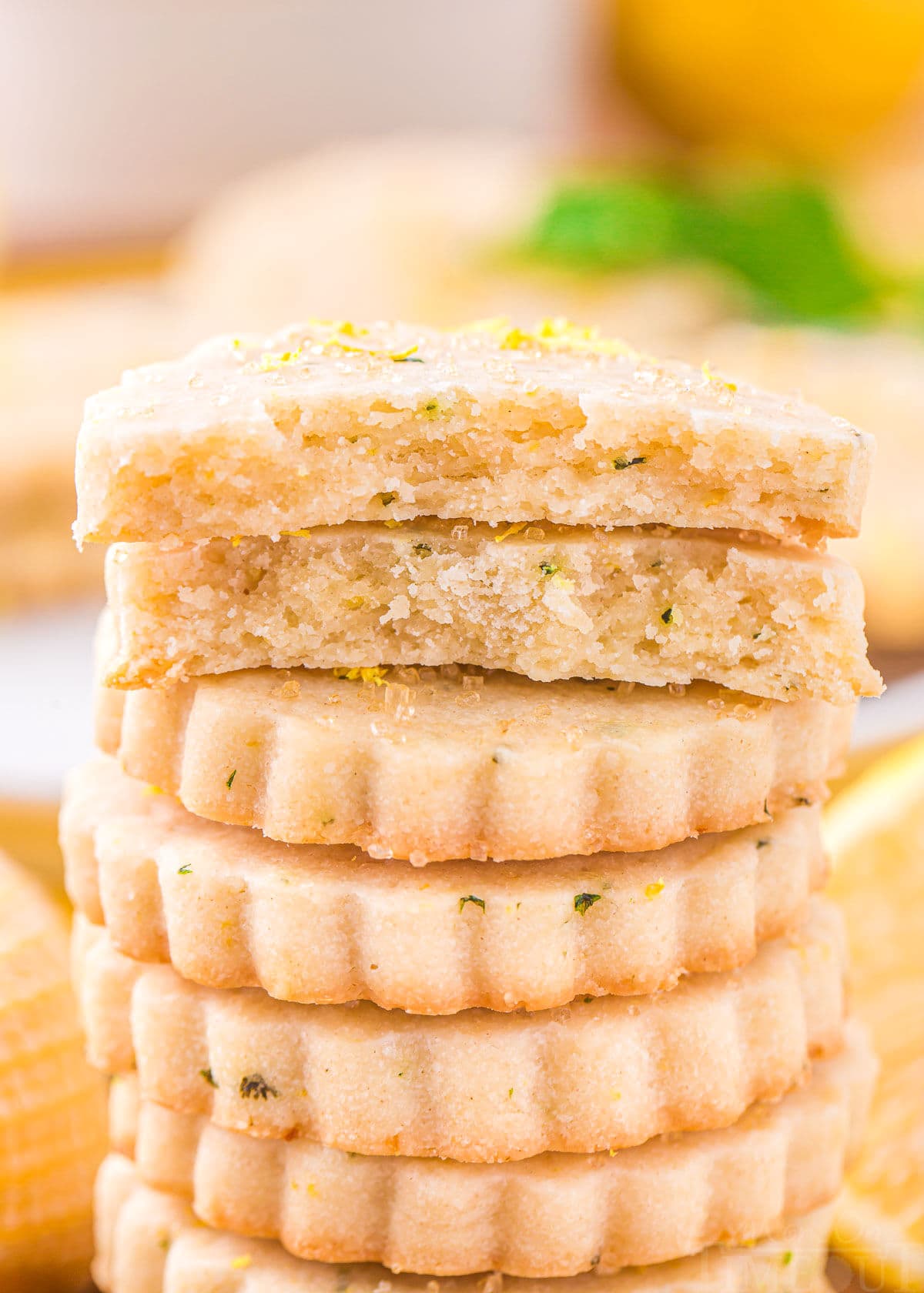 lemon shortbread cookies stacked about 10 high with the top cookie broken in half.