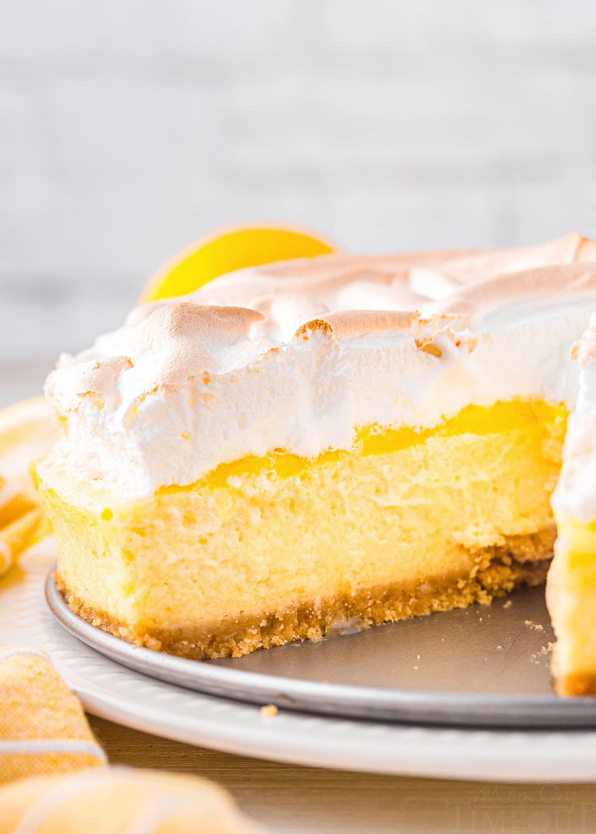 whole lemon meringue cheesecake with a slice removed sitting near a yellow napkin.