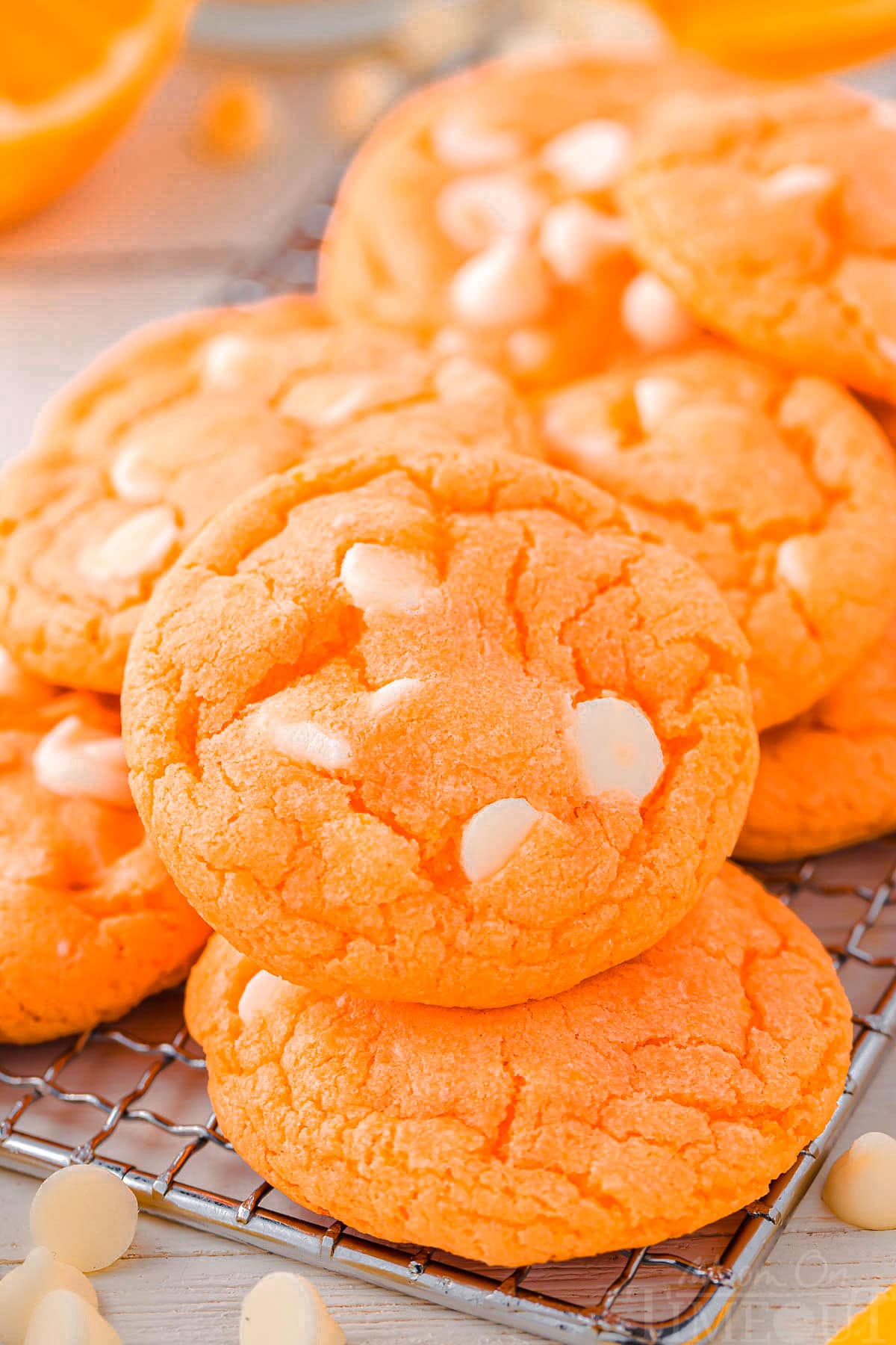 orange creamsicle cookies on a cooling rack with white chocolate chips scattered about.