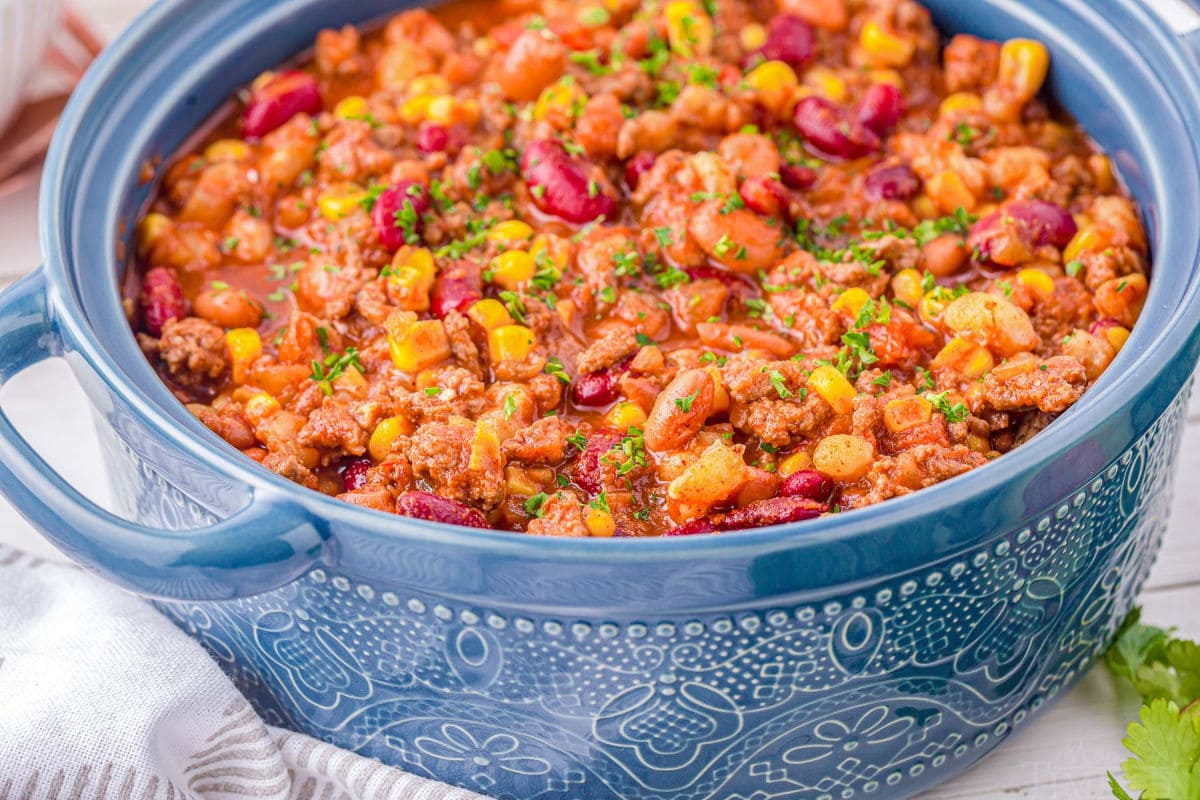 blue dutch oven filled to the brim with taco soup made with beef and beans.