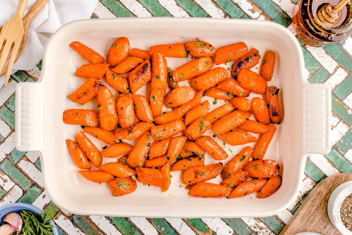 top down look at honey roasted carrots in white baking dish.