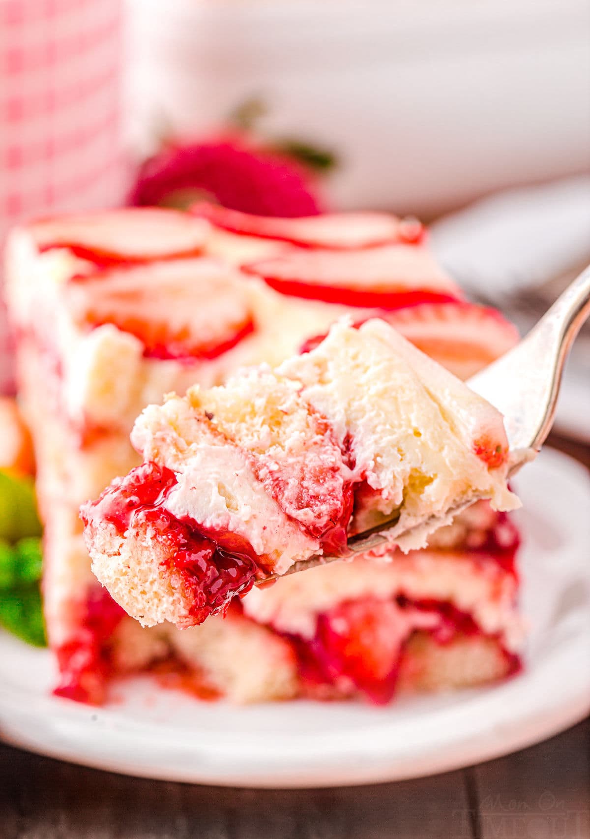 fork holding up a bite of strawberry tiramisu showing all the pretty layers.